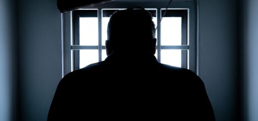 Image of man standing in front of caged window
