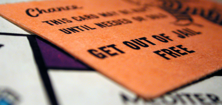 Closeup at an angle photo of the an orange 'get out of jail free' card on a monopoly game board