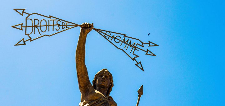 A statue of a woman holding aloft stylized arrows that spell out "Droits de l'homme" which is "Rights of Man" in French.